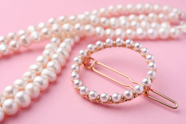 ピンクの背景のエレガントな真珠の髪のクリップとネックレス クローズアップ — ストック写真