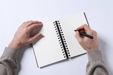 Man with pen and empty notepad on white background, top view