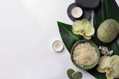 Spa taşları, deniz tuzu ve güzel çiçeklerle bembeyaz bir masa üzerinde düz bir kompozisyon sergiliyordu. Metin için boşluk