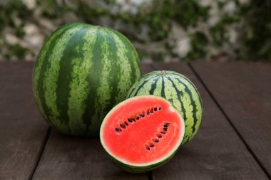 Lezzetli bir kesik ve olgun karpuzlar ahşap masada.