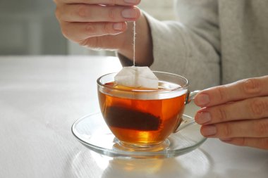 Kadın çay poşetini dışarı çıkarıyor. Kapalı bir masada, yakın plan.