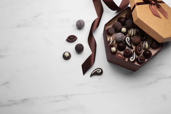白い大理石のテーブルの上においしいチョコレートキャンディーと茶色のリボンのオープンボックス フラットレイアウト テキストのスペース — ストック写真
