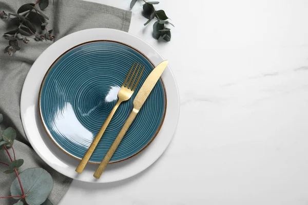 stock image Stylish setting with cutlery and eucalyptus leaves on white marble table, flat lay. Space for text