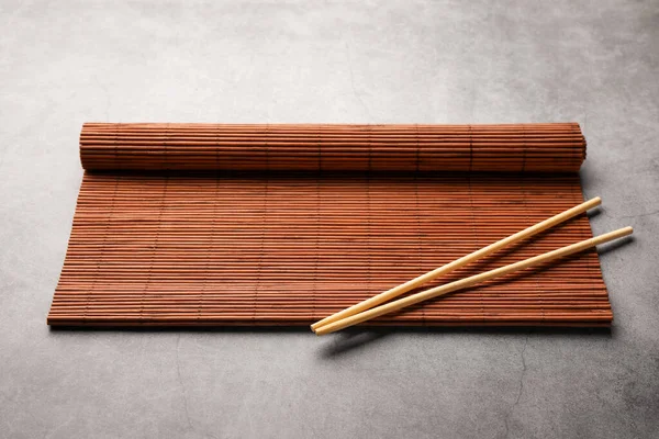 stock image Rolled bamboo mat and chopsticks on grey table