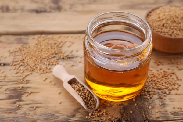 stock image Jar of natural oil and mustard seeds on wooden table. Space for text