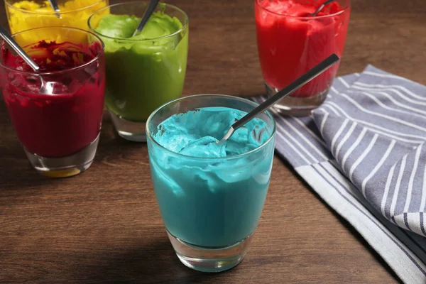 木製のテーブルの上に食べ物の着色と異なるクリームの眼鏡 — ストック写真