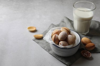 Doldurulmuş ceviz şeklinde kurabiyeler ve gri masada süt. Metin için boşluk