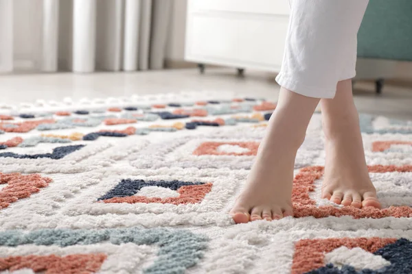 Woman standing on carpet with pattern at home, closeup. Space for text