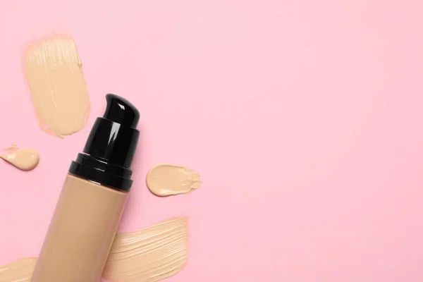 Liquid foundation and swatches on pink background, top view. Space for text