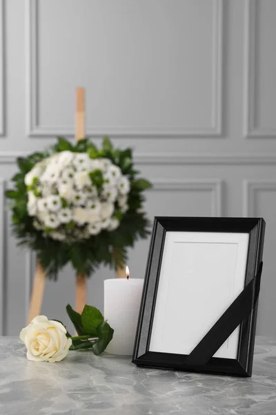 黒いリボン ライトグレーのテーブルの上にろうそくを燃やし 壁の近くの花の花輪を屋内で写真フレーム 葬儀の属性 — ストック写真
