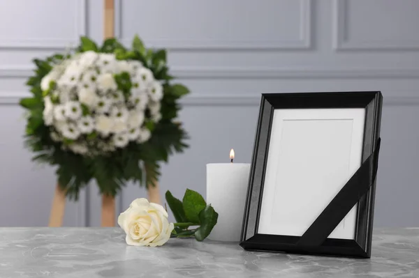 黒いリボン ライトグレーのテーブルの上に燃えるろうそくと壁の近くの花の花輪を持つ写真フレーム室内 テキストのためのスペース 葬儀の属性 — ストック写真