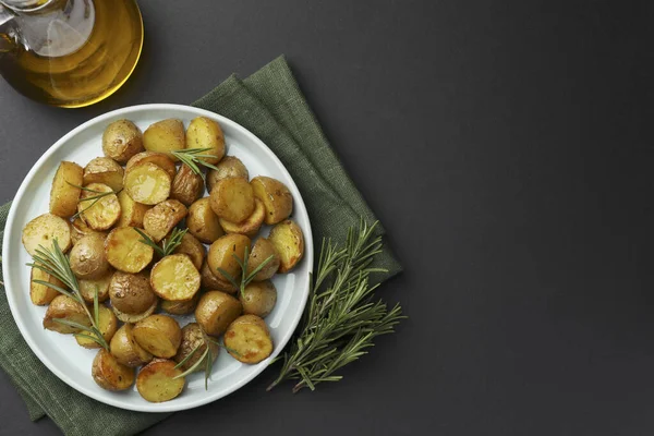 美味的烤土豆与迷迭香和油在黑色桌子上 顶部视图 案文的篇幅 — 图库照片