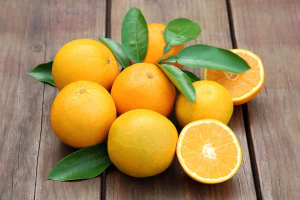 Viele Reife Orangen Und Grüne Blätter Auf Holztisch — Stockfoto