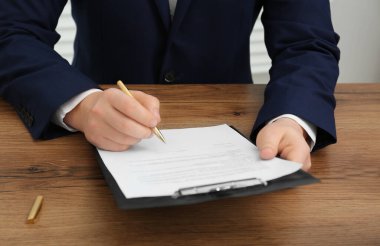 Ahşap masada belge imzalayan adam, yakın plan