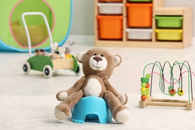 Odadaki açık mavi bebek lazımlığında sevimli bir oyuncak ayı. Tuvalet eğitimi