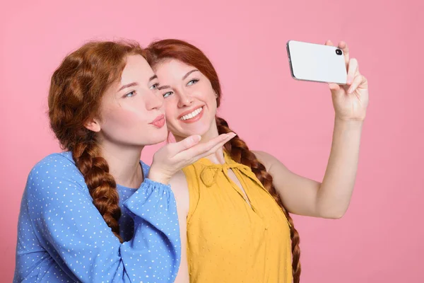 Güzel Kızıl Saçlı Kız Kardeşler Pembe Arka Planda Selfie Çekiyorlar — Stok fotoğraf