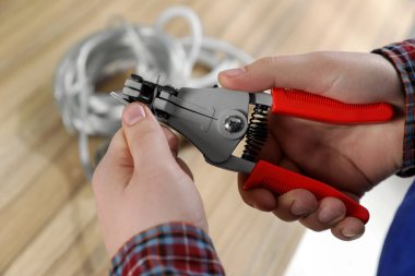 Professional electrician stripping wiring at wooden table, above view