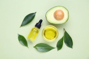 Temel yağ, taze kesilmiş avokado ve açık yeşil arka planda yapraklar.