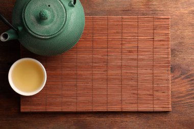 Bambu hasırı, çaydanlık ve çay, ahşap masa, üst manzara. Metin için boşluk