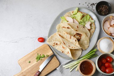 Pide dürümü yapıyorum. Lezzetli tortilla, tavuk, marul ve diğer malzemeler açık gri masa, düz yatak. Metin için boşluk