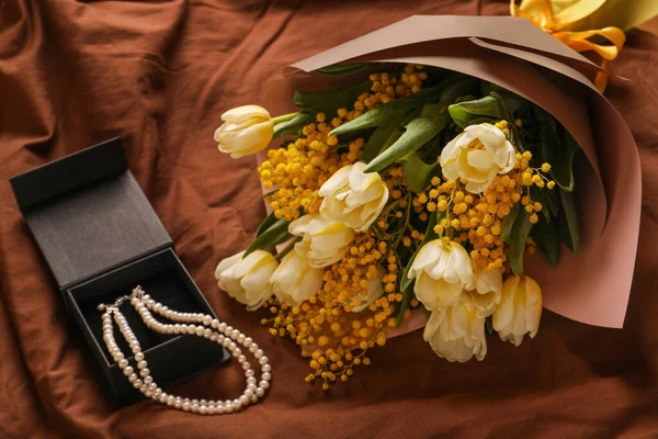 一束簇美丽的春花和项链挂在褐色面料上 俯瞰上方 — 图库照片