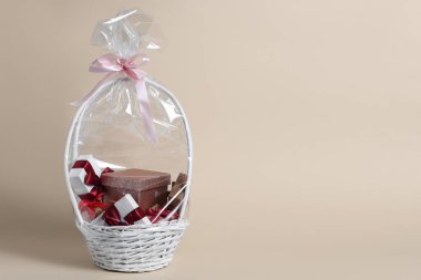 Bej arka planda hediye kutularıyla dolu bir sepet. Metin için boşluk