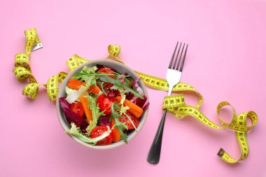 Pembe arka planda mezurası olan sağlıklı bir salata. Diyet kavramı