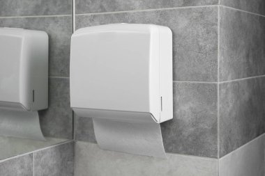 Banyoda aynanın yanında duvarda asılı duran yeni kağıt havlu makinesi.