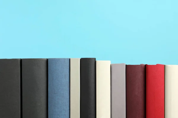 Many different hardcover books on light blue background, space for text