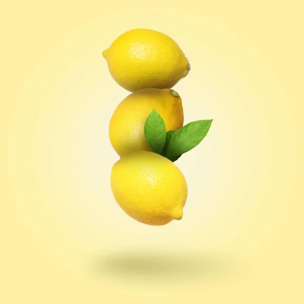 Целые Свежие Лимоны Зелеными Листьями Падают Бледный Золотистый Фон — стоковое фото