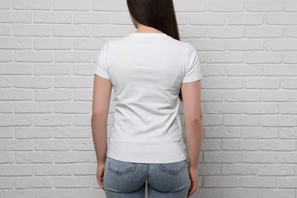 白いレンガの壁の近くにスタイリッシュなTシャツを着ている女性 クローズアップ — ストック写真