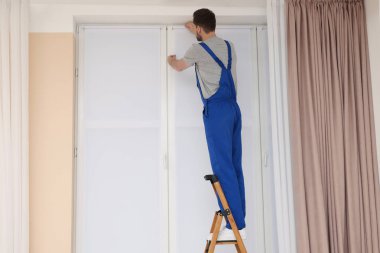 Üniformalı işçiler içerideki merdivene paten penceresi kuruyor.