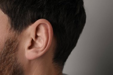 Gri arka plandaki adam, kulağı kapat.