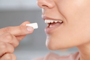 Bulanık arka planda sakız çiğneyen kadın, yakın plan.