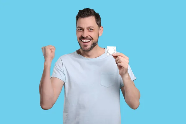 Homem Emocional Segurando Preservativo Fundo Azul Claro — Fotografia de Stock