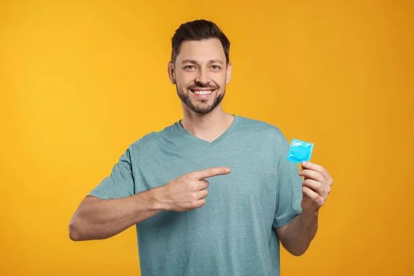 Homem Feliz Segurando Preservativo Fundo Laranja — Fotografia de Stock