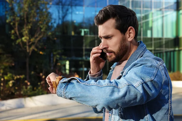Emocjonalny Mężczyzna Rozmawiający Smartfonie Patrzący Zegarek Pobliżu Budynku Spóźniona Koncepcja — Zdjęcie stockowe