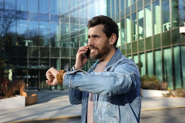 Συναισθηματικός Άντρας Μιλάει Στο Smartphone Και Κοιτάζει Ρολόι Κοντά Στο — Φωτογραφία Αρχείου