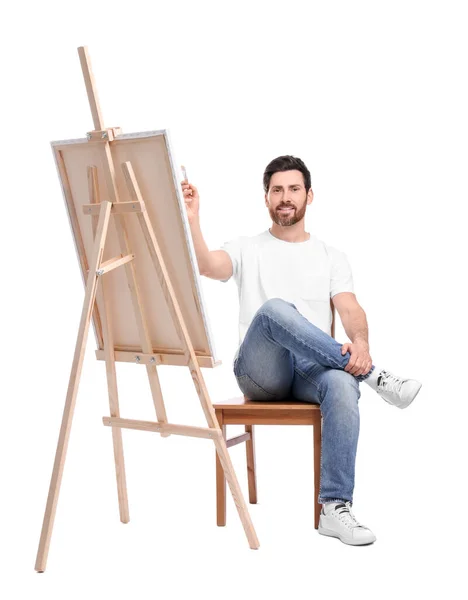 白を背景に筆で幸せな男の絵 キャンバスを保持するためにイーゼルを使用 — ストック写真