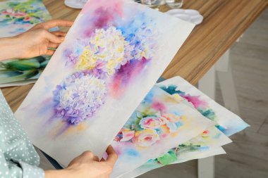 Kapalı alanda çiçek boyayan bir kadın, yakın plan. Suluboya sanat eserleri