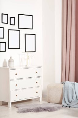 Beyaz duvarda asılı boş çerçeveler, çekmeceler ve kapalı kapılar.
