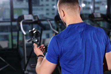 Spor salonunda, arka planda egzersiz yapan bir adam var. Çevrimiçi fitness eğitmeni