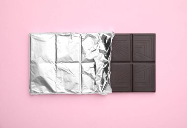 Tasty chocolate bar on pink background, top view