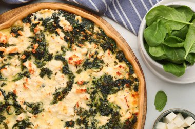 Lezzetli ev yapımı ıspanaklı kiş ve malzemeler beyaz masada, düz yerde.