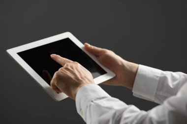Gri arkaplanda yeni tablet kullanan adamın yakın görüntüsü