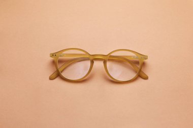 Açık kahverengi zemin üzerinde düzeltici lensli gözlük, üst görünüm
