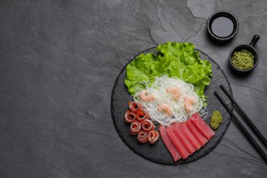 Sashimi seti (çiğ ton balığı, somon balığı ve karides) funchosa, marul, vasabi ve soya sosuyla servis edilir. Metin için boşluk