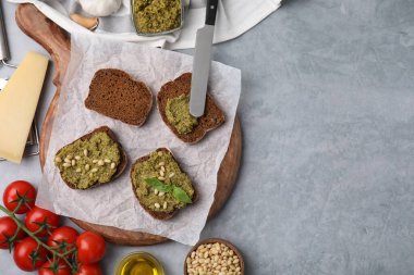 Pesto soslu nefis bruschettalar, fındıklar ve açık gri masada taze fesleğenler, düz yatak. Metin için boşluk