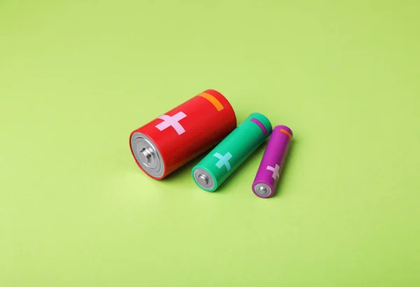 stock image Batteries of different sizes on light green background