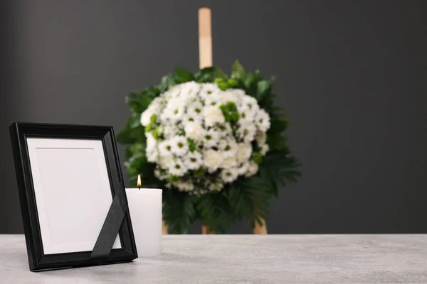 黒いリボンで写真フレーム テーブルの上にろうそくを燃やし 屋内で灰色の壁の近くの花の花輪 テキストのためのスペース 葬儀の属性 — ストック写真